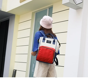 Outdoor shot of the tricolor backpack featuring red front pocket and blue straps
