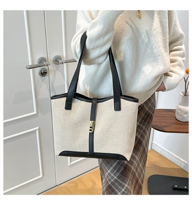 Detail of canvas tote bag with black leather trim and gold buckle shown on shoulder