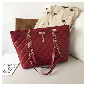 Detail of burgundy quilted tote bag with golden chain strap and deer charm decoration
