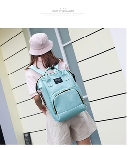 Outdoor shot of a mint green multi-functional diaper backpack on a model back