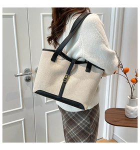 Detail of canvas tote bag with black leather trim and golden metal twist lock closure