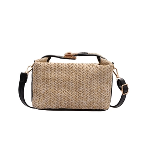 Woven straw top handle bag with black leather straps and gold buckle closure