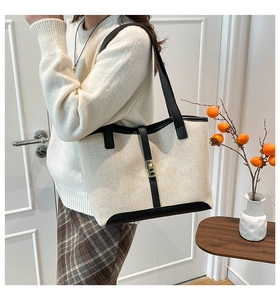 Detail view of contrast stitch canvas tote bag with black leather trim and gold metal lock