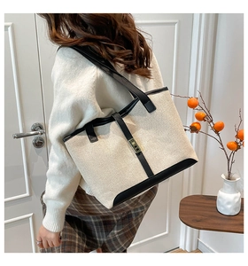 Detail of canvas tote bag with black leather trim and gold buckle shown on shoulder