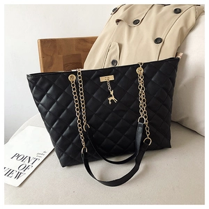 Detail of black quilted tote bag with gold chain strap and signature deer charm