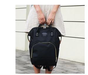 Detail of a black large-capacity mommy backpack with dual handles and golden zipper