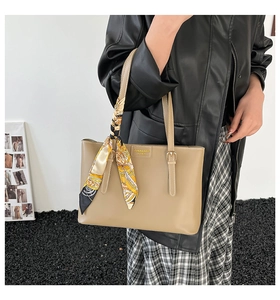 Close-up of khaki tote bag with fashion leather tag and decorative printed silk scarf handle