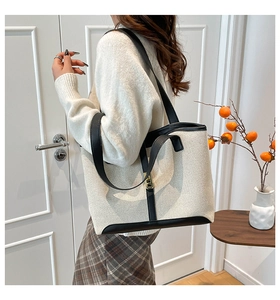 Detail of canvas tote bag with black leather trim and elegant gold metal hardware buckle