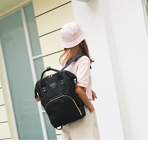 Close-up of black multifunction mommy backpack with durable top handles and logo patch