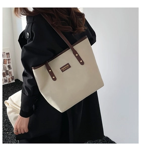 Detail of the high-capacity canvas tote bag with brown leather trim and square logo patch