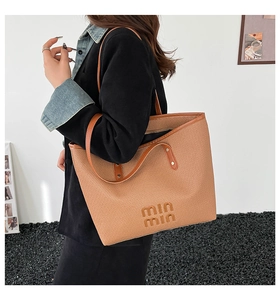 Detailed close-up of woven tote bag with leather strap and embossed min min logo texture