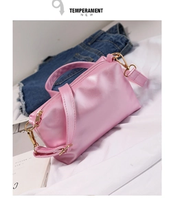 Dettaglio di una mini borsa a bauletto rosa lucida in ecopelle con cinturino e parti dorate