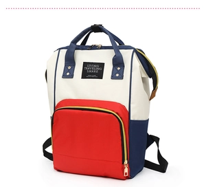 Close-up of tricolor diaper backpack with Living Traveling Share label and metal zippers