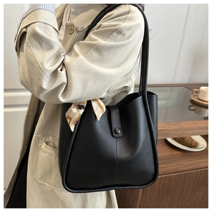Detail of black pebbled leather bucket bag featuring a decorative beige floral silk scarf
