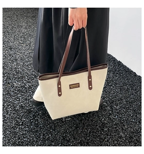 Close-up of contrast stitching on a beige tote bag with dark brown leather handles