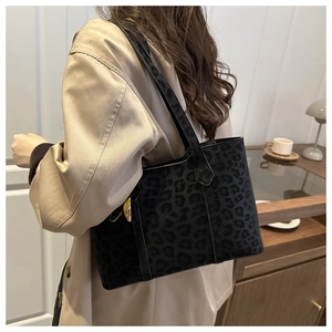 Detail of leopard print tote bag with black leather straps on a khaki trench coat