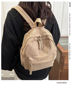 Detail of khaki corduroy backpack on model showing woven zipper pull and side pockets