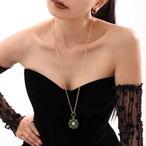 Golden snowflake pendant necklace set with green enamel and zircon stones on a model
