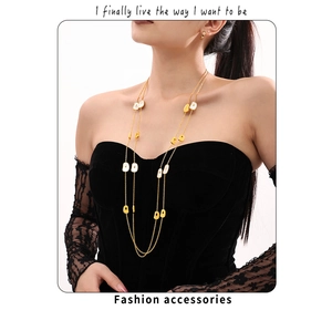 Detail of a layered long gold necklace with white shell rectangle charms on a model