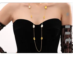 Detail of a long stainless steel gold necklace with natural white shells on a model