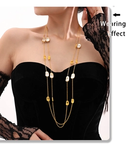 Close-up of double-layered long necklace with white shell oval pendants on golden chain