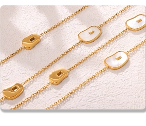 Macro detail of gold stainless steel necklace featuring natural white seashell charms