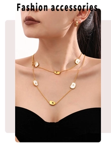 Detailed shot of gold layered necklace with white shells and matching hoop earrings