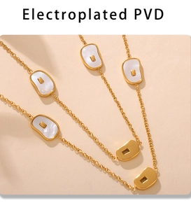 Detail of PVD plated gold necklace featuring natural white seashell inlays and hollow charms