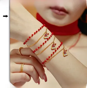 Dettaglio del bracciale con ciondolo a cappello di Natale e perline rosse oro