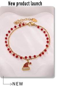 Dettaglio di un bracciale a doppio strato in acciaio inossidabile con perle rosse e ciondolo natalizio