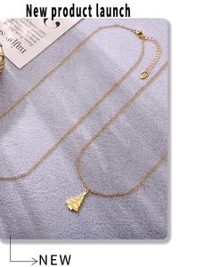 Macro view of gold christmas tree pendant with white crystals on a gold chain necklace