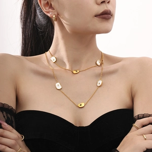 Elegant gold double layer necklace with white sea shell charms and small hoop earrings