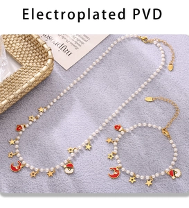 Macro detail of PVD plated stainless steel pearl necklace with festive enamel charms