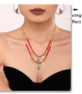 Detail of model wearing a layered Christmas necklace with enamel charms and gold hoop earrings