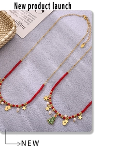 Detailed view of Christmas necklace with enamel tree, snowflake pendants and red beads