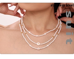 Gros plan sur un collier de perles à trois rangs avec pendentifs marguerites en acier