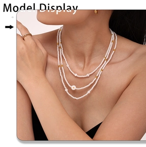 Mannequin portant un collier de perles multicouches avec charms marguerites et or