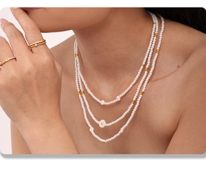 Gros plan sur un collier de perles à trois rangs avec pendentifs marguerites