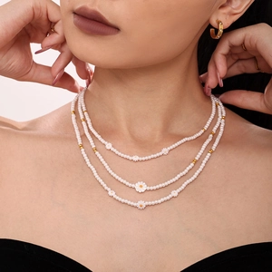 Dreilagige Kunstperlenkette mit weißem Gänseblümchen-Anhänger und goldenen Akzenten am Model