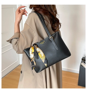 Detail of black leather tote bag with white contrast stitching and floral silk scarf handle