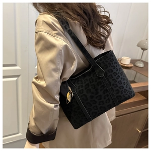 Detail of black leopard print tote bag with silk scarf accessory on a shoulder