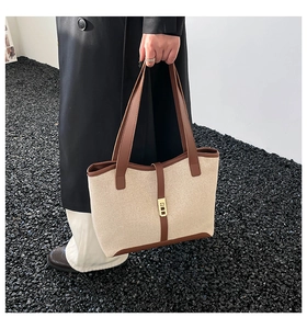 Spacious beige canvas tote bag with brown leather trim and metallic lock detail