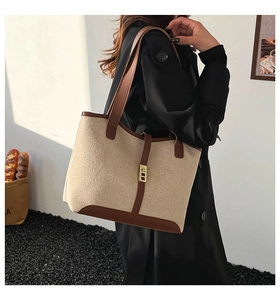 Close-up of contrast tote bag featuring linen canvas, brown leather trim, and gold buckle