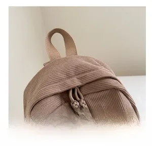 Detail view of corduroy backpack featuring smooth double zippers and woven rope pulls