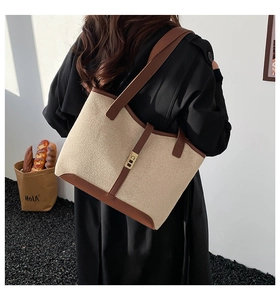 Detail of a beige canvas and brown leather tote bag with golden buckle on a model shoulder