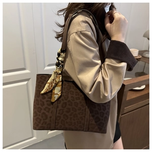 Close-up of leopard print tote bag featuring a decorative silk scarf on the handle
