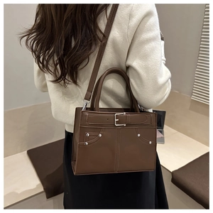 Detail of dark brown leather square bag with decorative rivet pocket and silver buckles