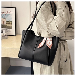 Schicke schwarze Leder-Tragetasche mit gepunktetem Seidentuch im Lifestyle-Ambiente