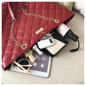 Detail of red quilted tote bag with gold chain showing spacious interior for essentials