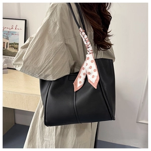 Detail einer schwarzen Leder-Shopper-Tasche mit gepunktetem Seidentuch am Schultergurt